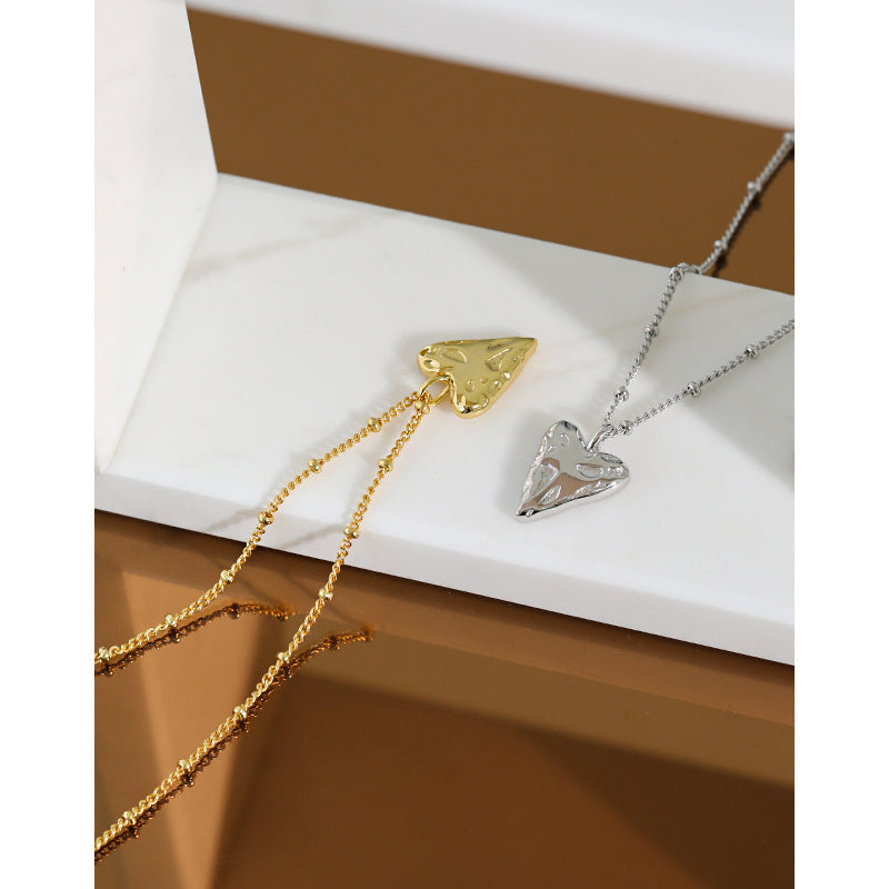 Gold and silver necklaces with heart pendants on a white surface.