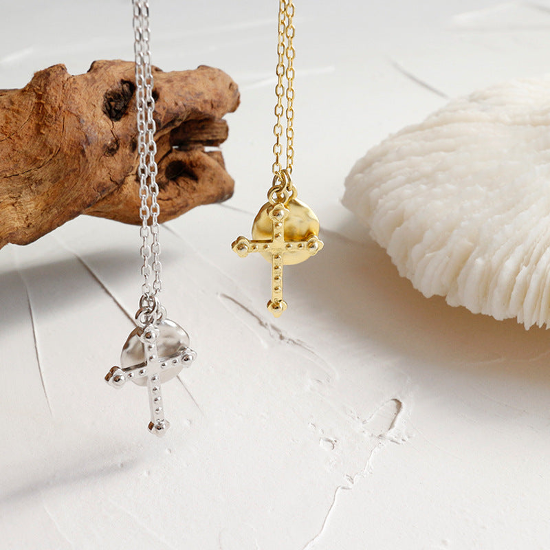 Gold and silver pendants on chains with natural elements like wood and shell in the background.