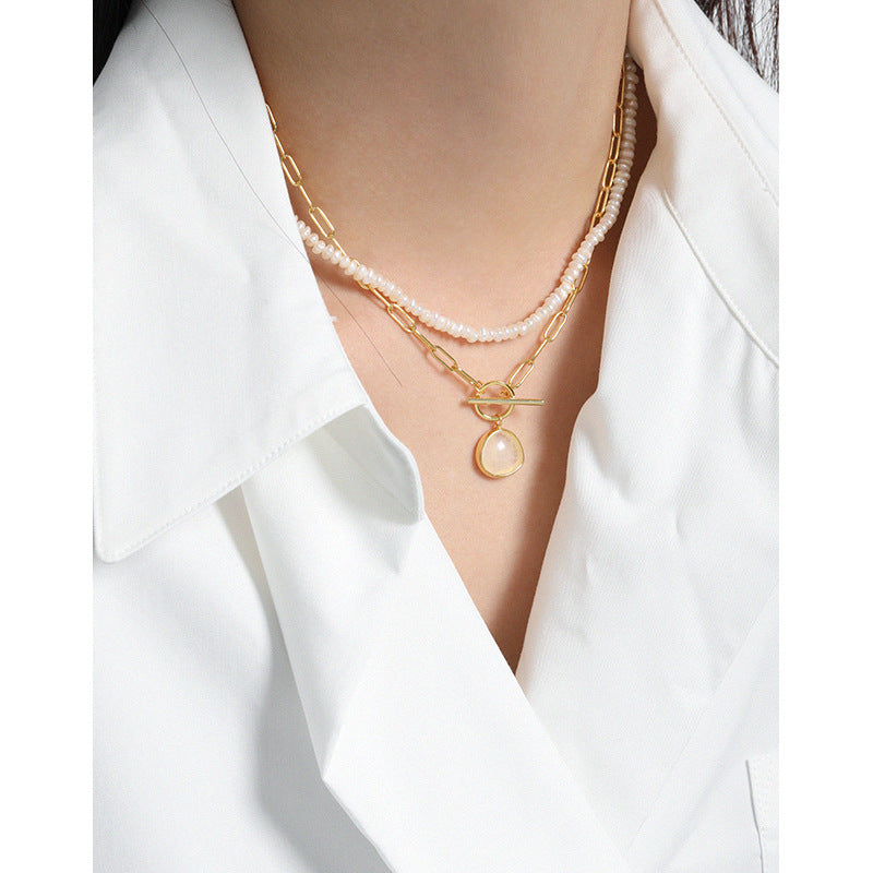 Gold necklaces with pearl pendants on a white shirt
