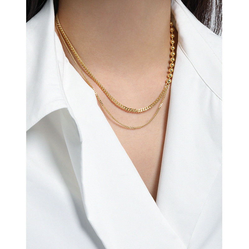 Gold necklace on a person wearing a white outfit