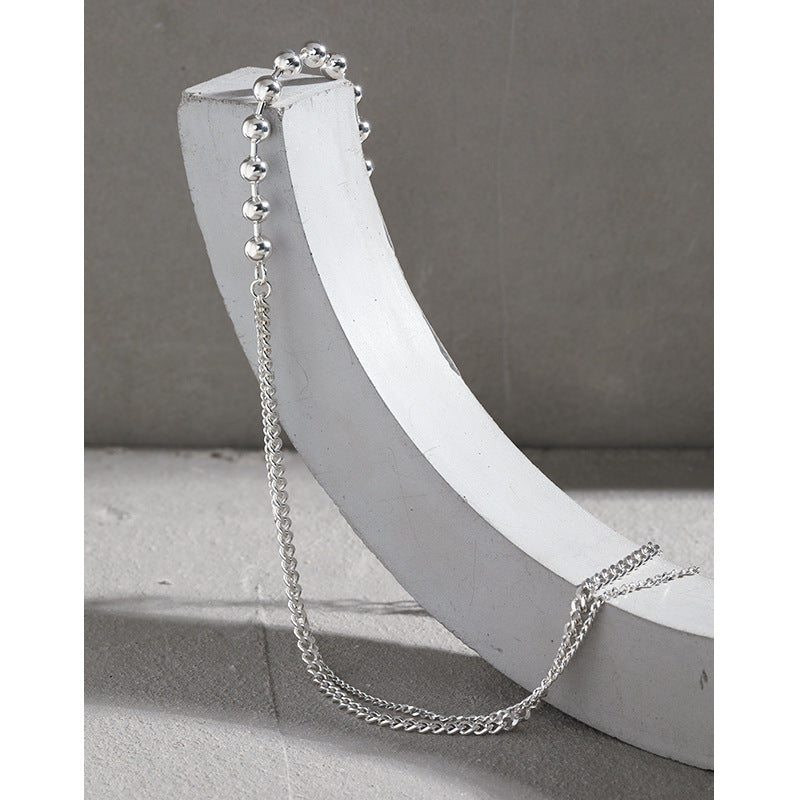 Silver chain necklace on a white stand against a gray background
