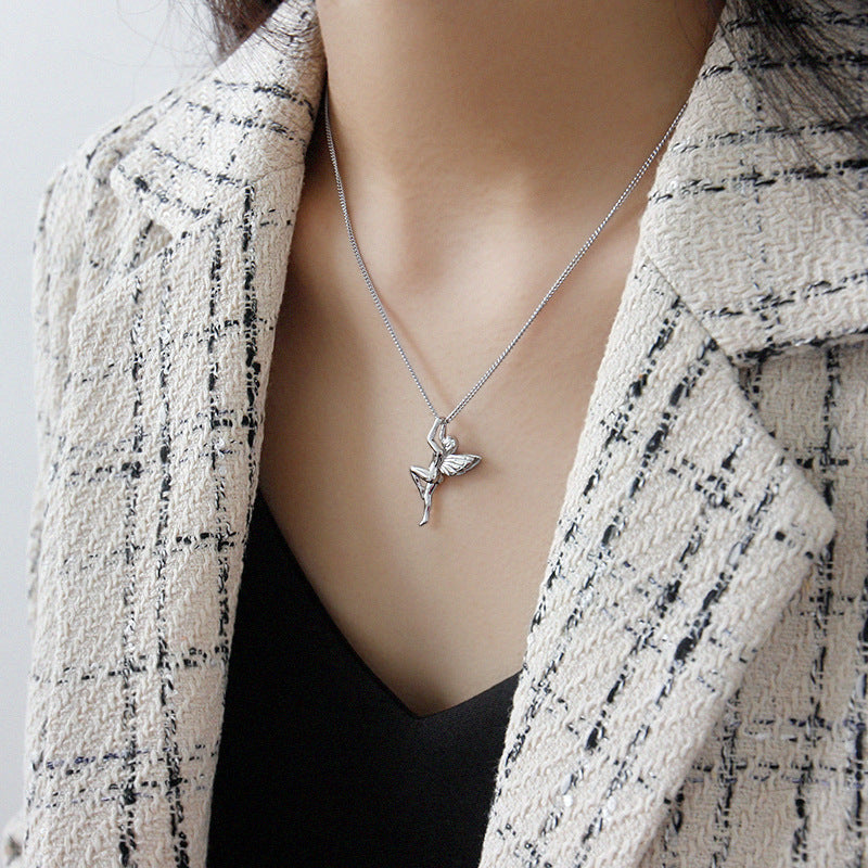 Person wearing a silver necklace with a fairy pendant against a neutral background