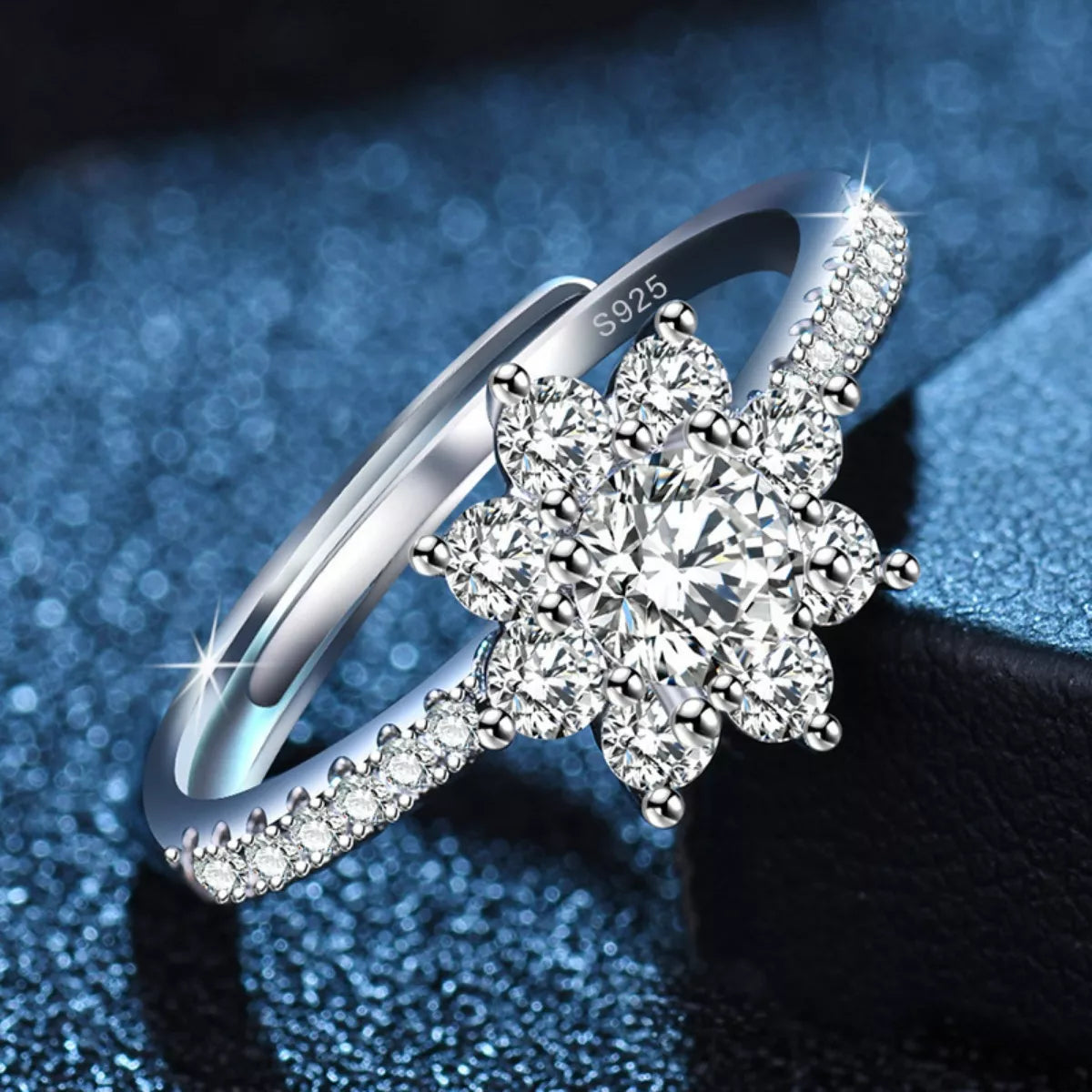 Silver ring with floral diamond design on a blue and black gradient background