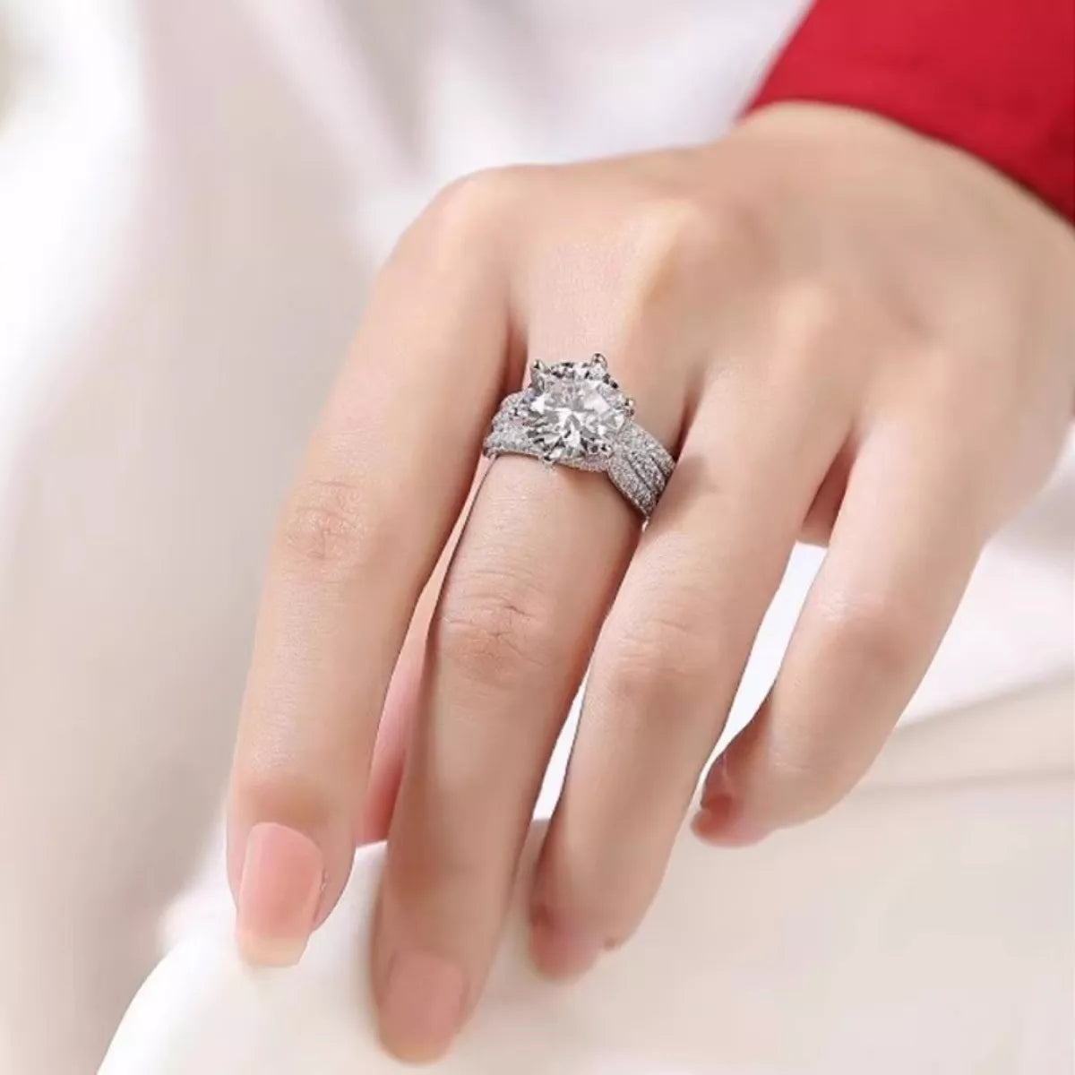 Close-up of a hand wearing a silver ring with a large diamond on a white background