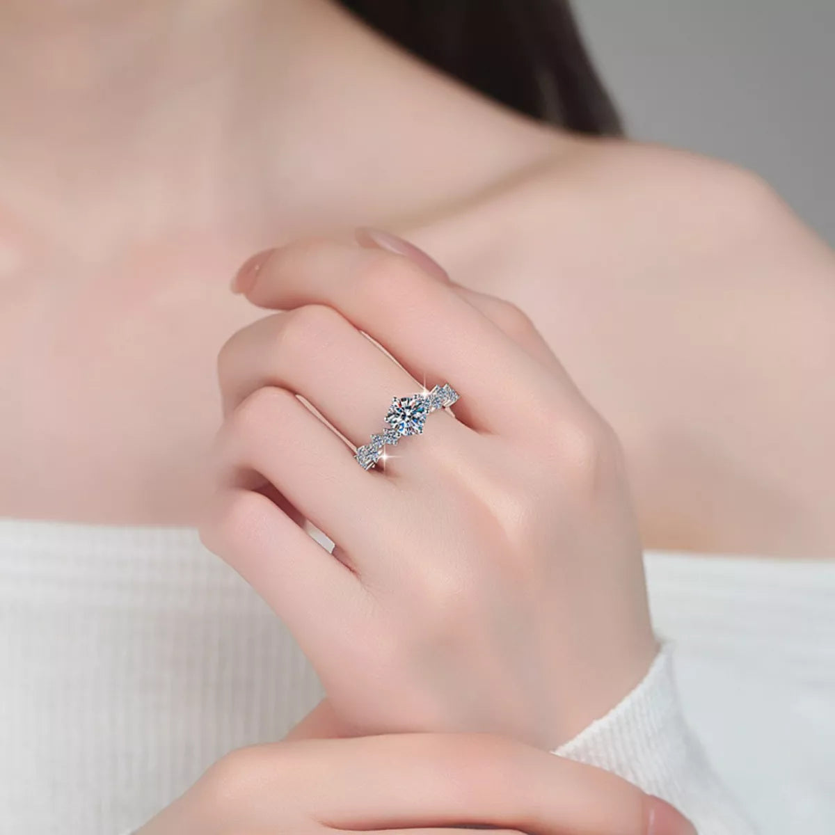 Close-up of a hand wearing a silver ring with a large gemstone on a neutral background