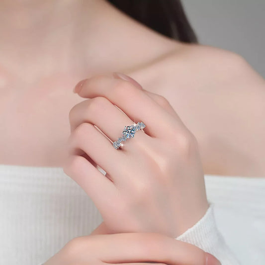 Close-up of a hand wearing a silver ring with a large gemstone on a neutral background