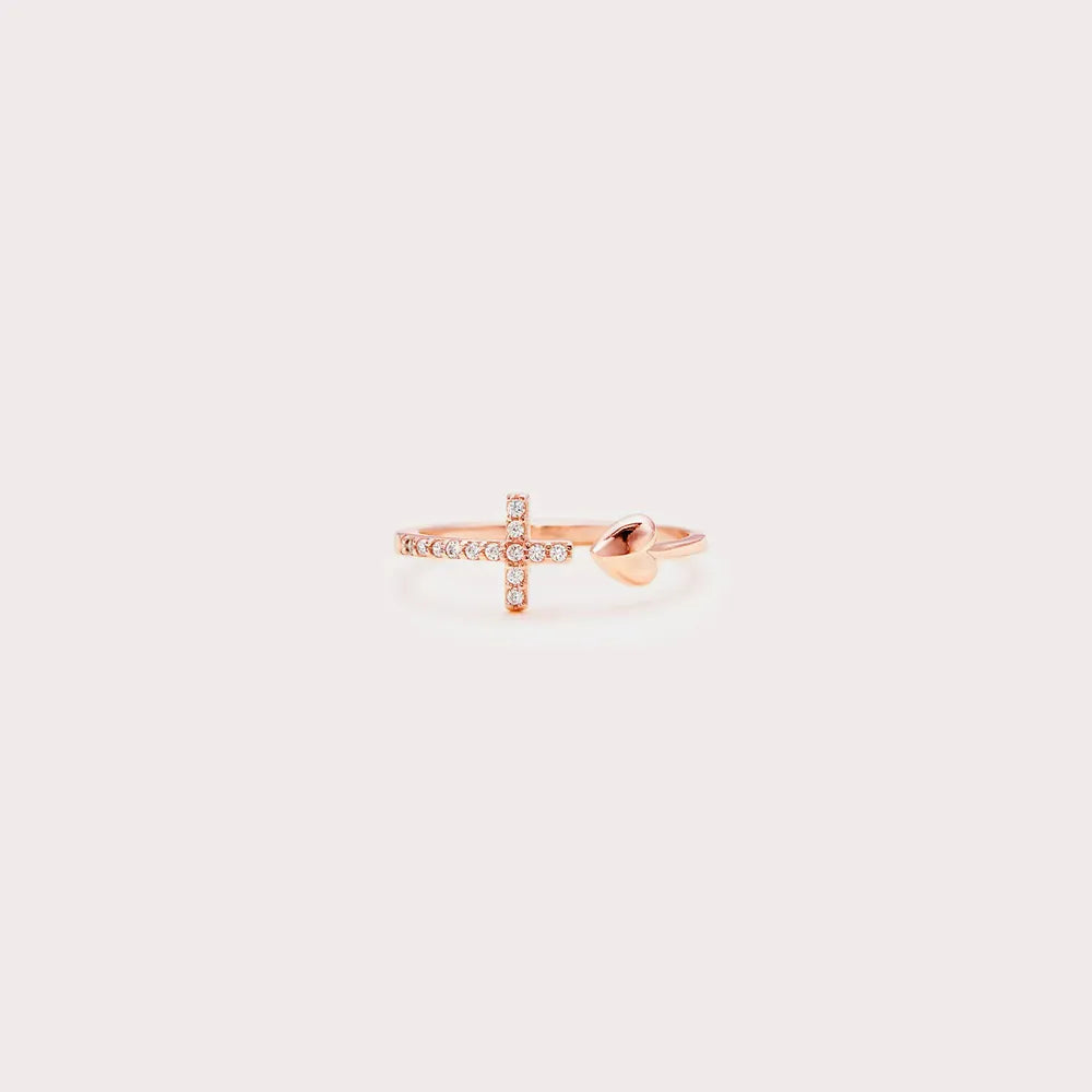 Rose gold cross-shaped ring on a light pink background