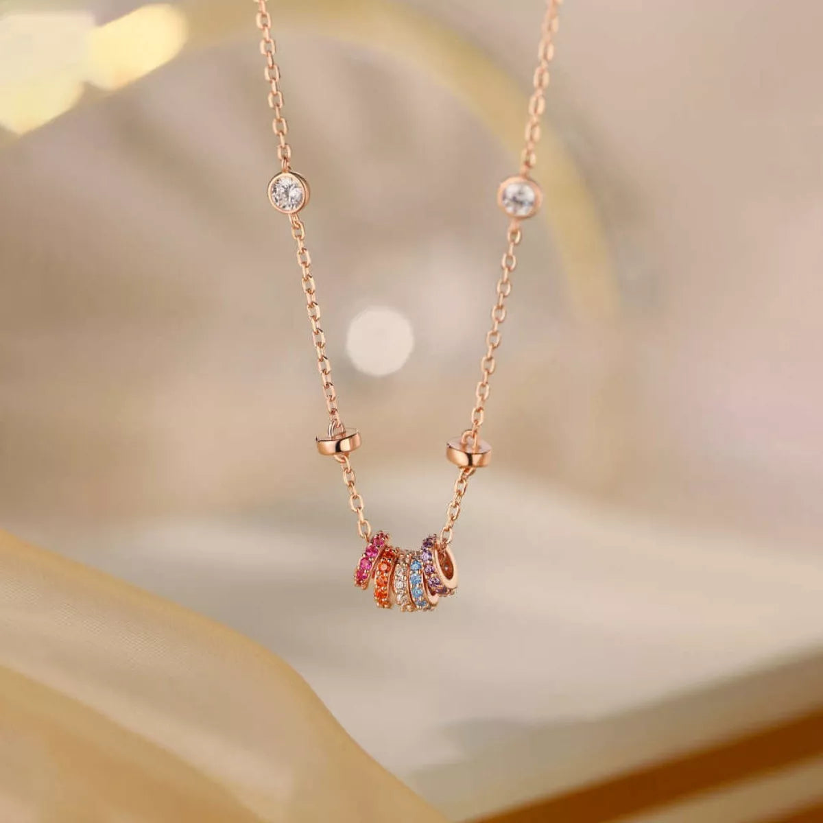 Delicate rose gold necklace with colorful gemstones on a soft background