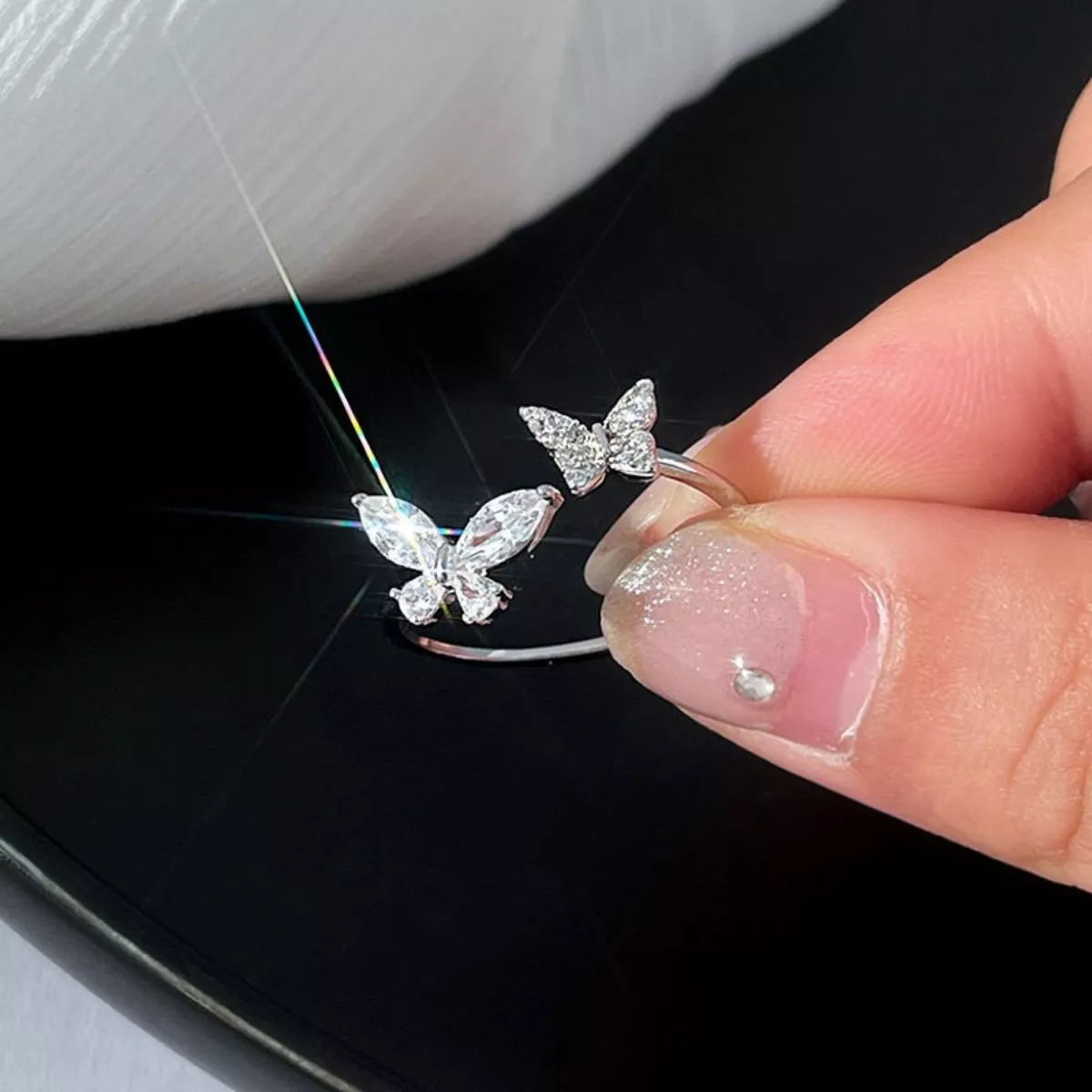 Butterfly-shaped earrings held by a hand against a dark background