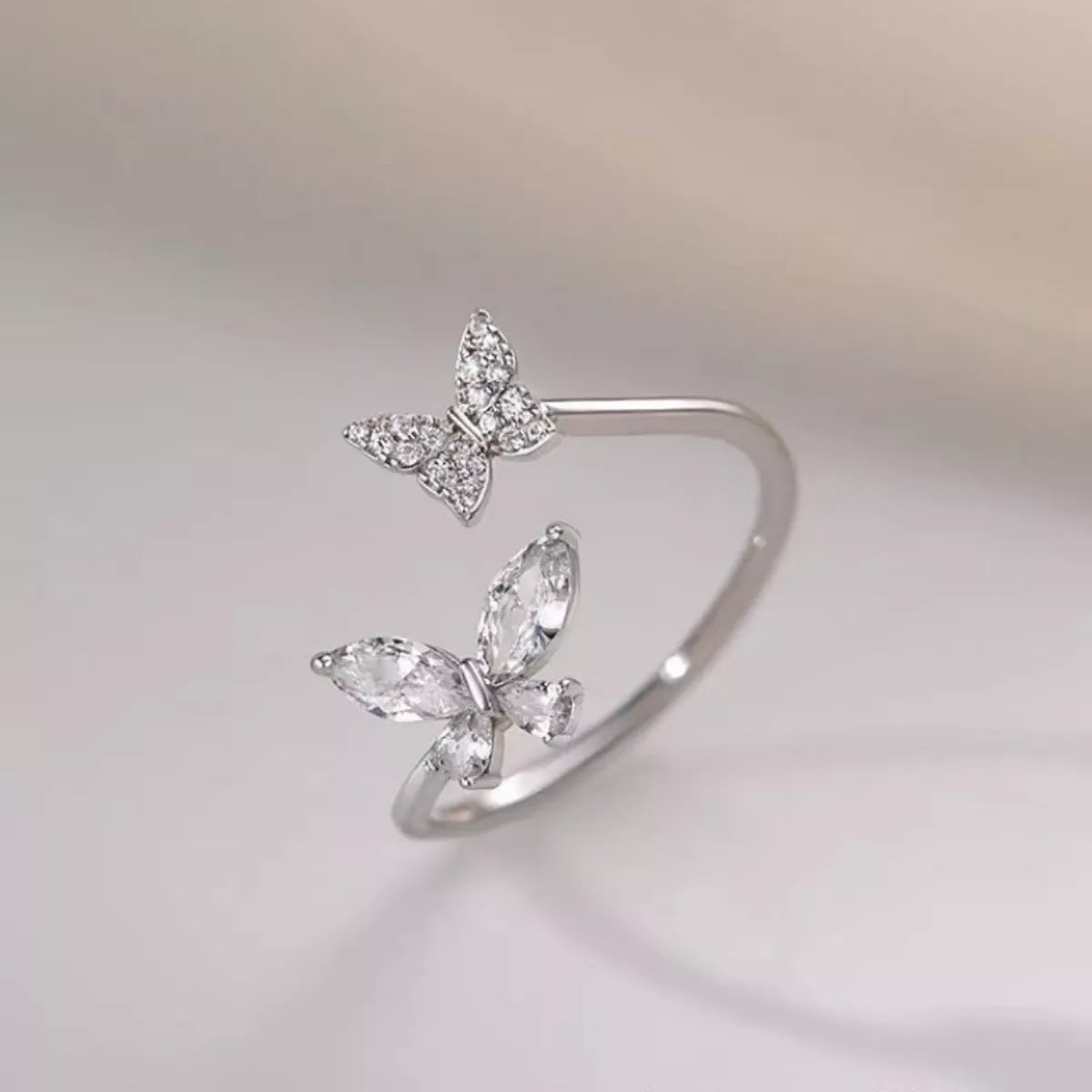 Silver butterfly-shaped ring on a light gray background