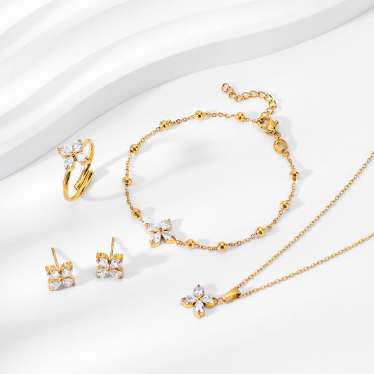 Gold geometric zircon bridal jewelry set featuring a necklace, bracelet, ring, and stud earrings arranged on a white surface.