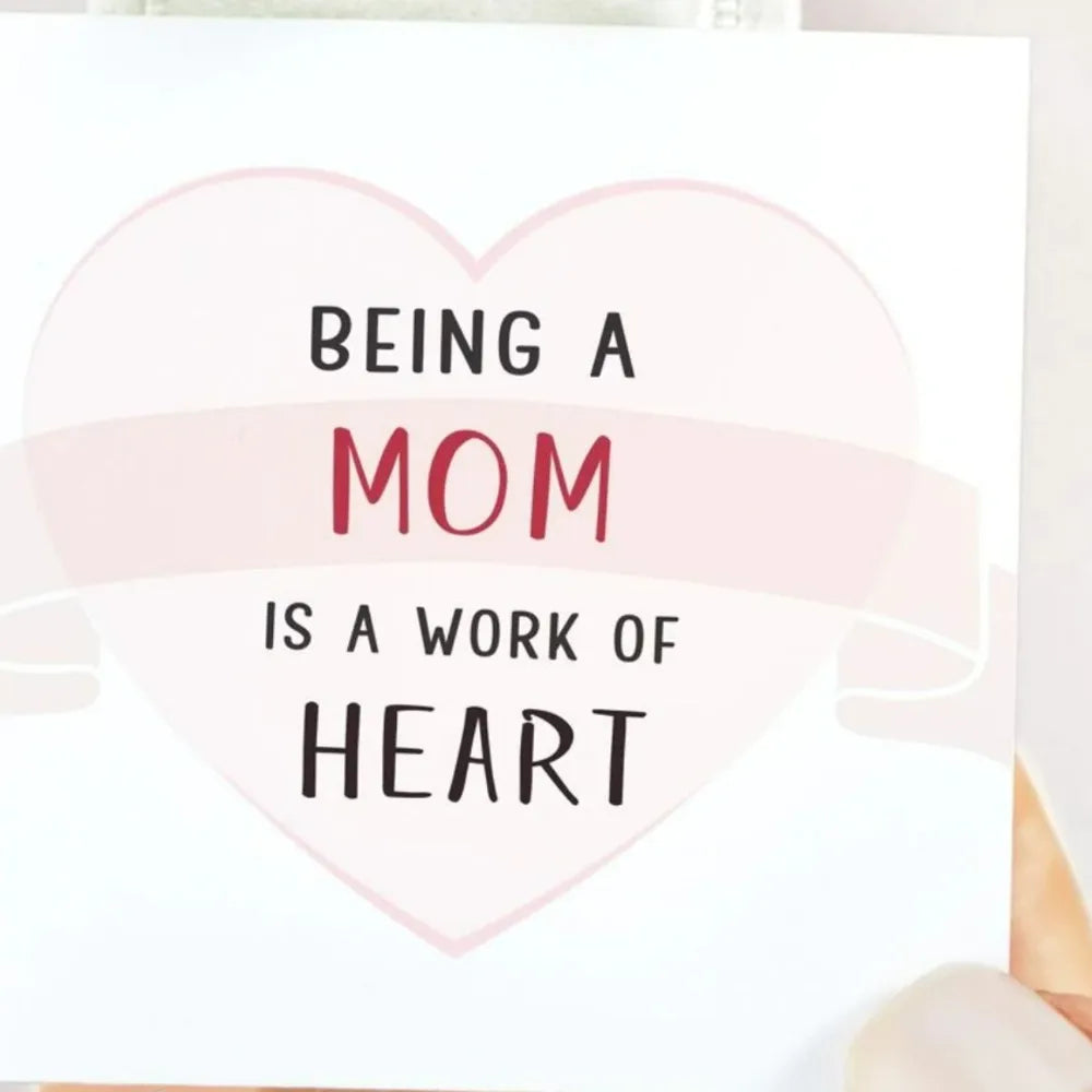 Heart-shaped card with 'Being a Mom is a Work of Heart' text on a white background