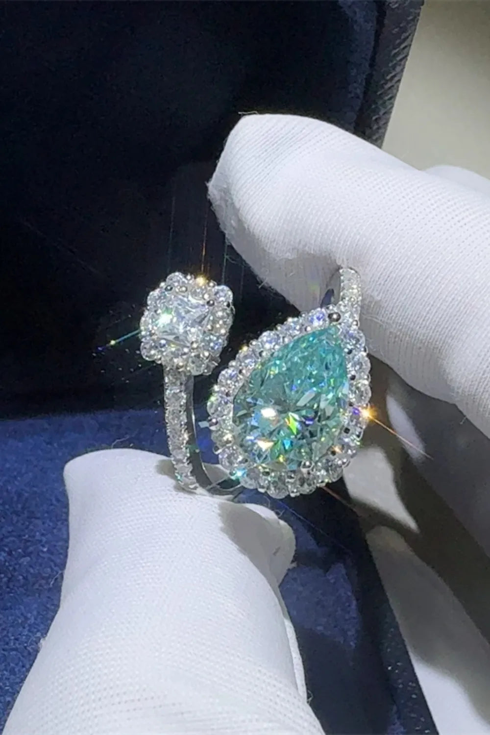 Diamond ring held by a gloved hand on a dark background