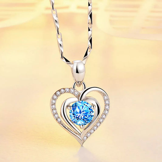 Silver heart-shaped pendant with a blue gemstone on a yellow background