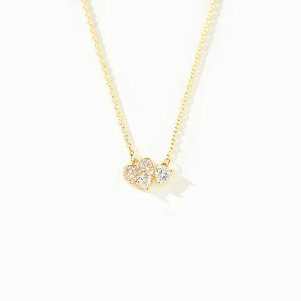 Gold necklace with a heart-shaped pendant on a white background