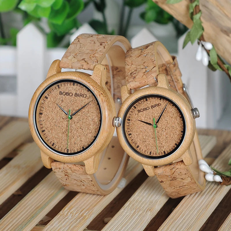 Two wooden watches with cork straps on a wooden surface.