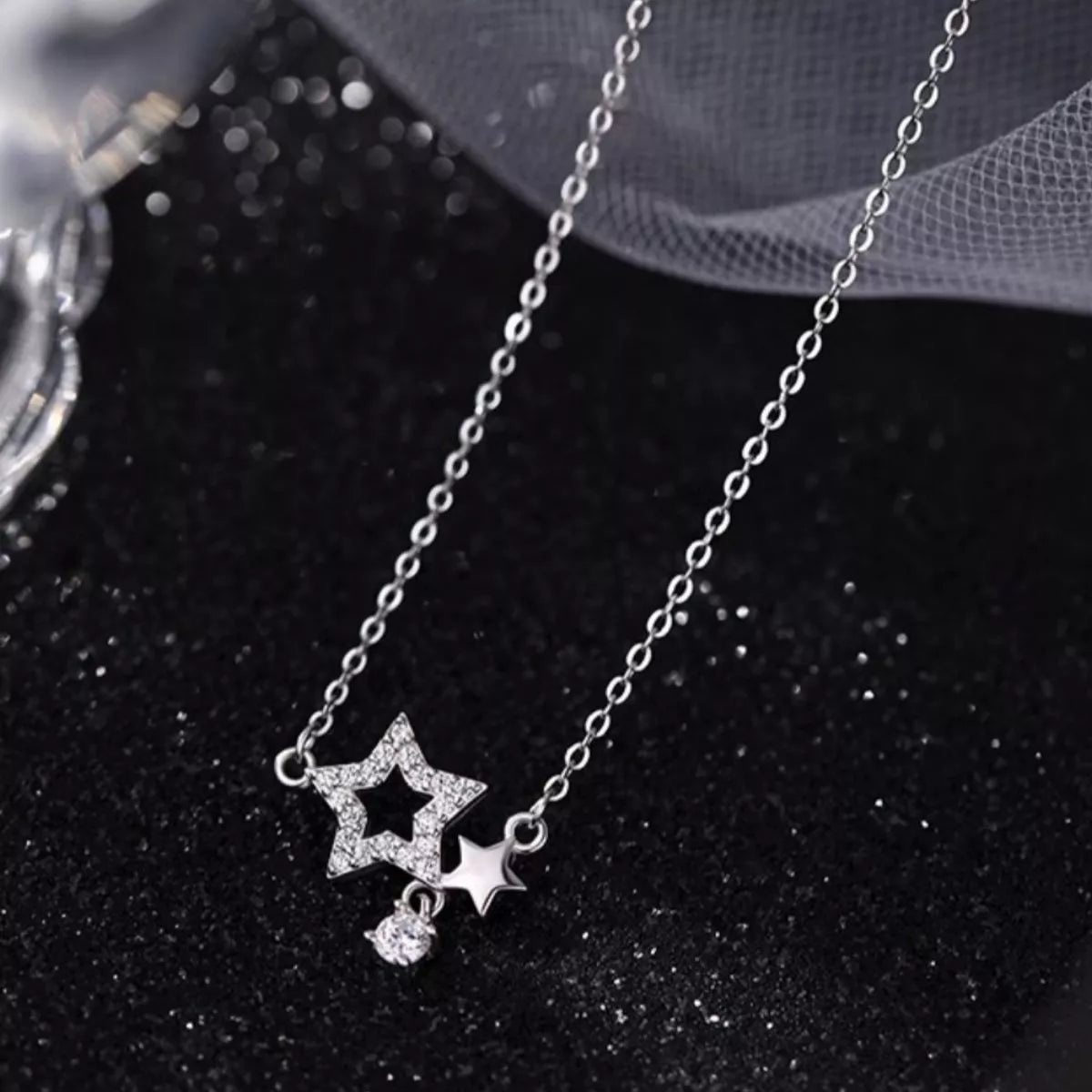 Silver necklace with star-shaped pendant on a dark background