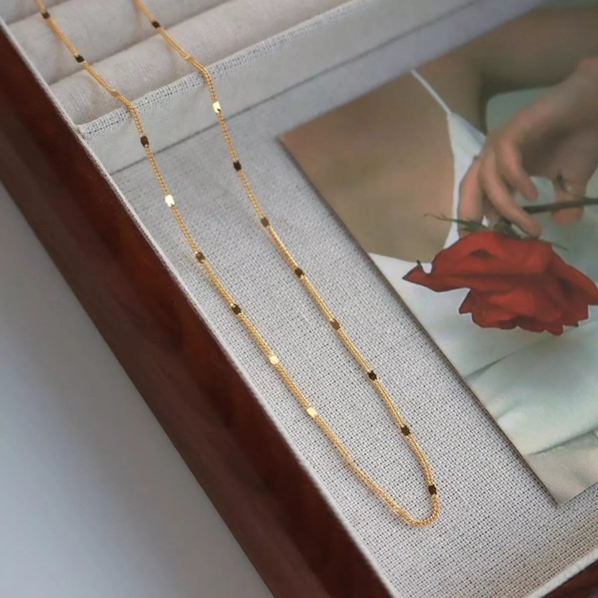 Gold chain necklace on a textured surface with a blurred background