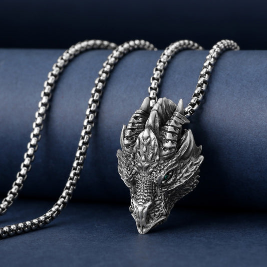 Silver dragon head pendant on a chain against a dark blue background