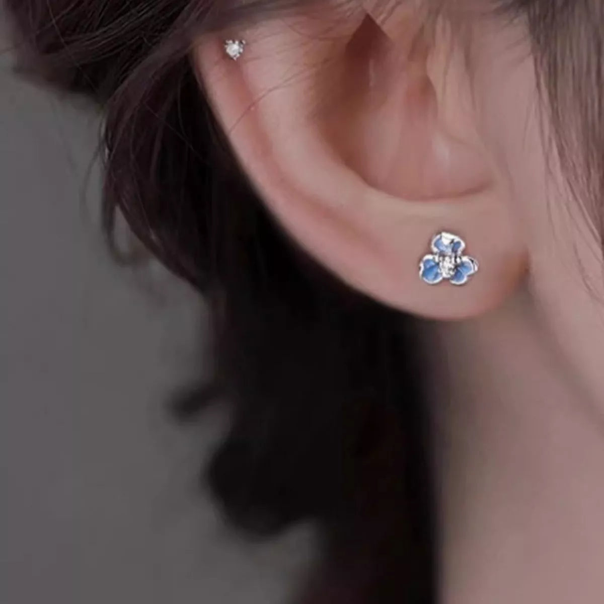 Close-up of an ear wearing a floral earring with a blurred background