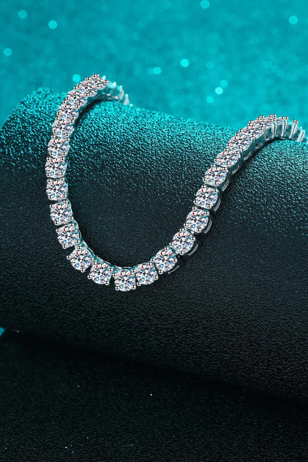 Silver bracelet with clear stones on a textured black surface