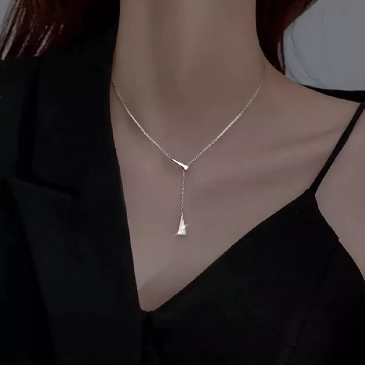 Silver necklace with a pendant on a person wearing a black top.
