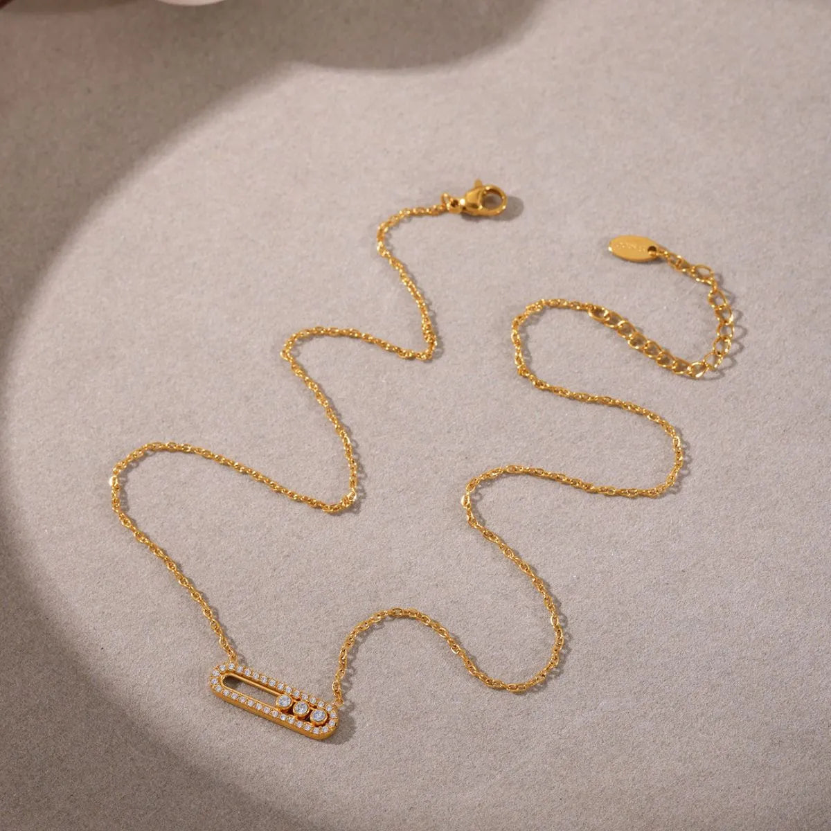 Gold necklace with a pendant on a beige surface