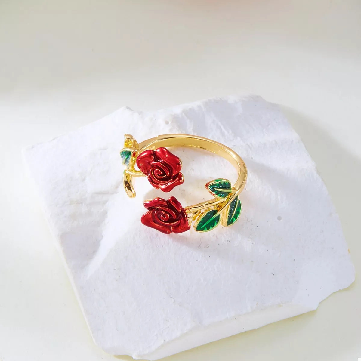 Gold ring with red roses on a white fabric background