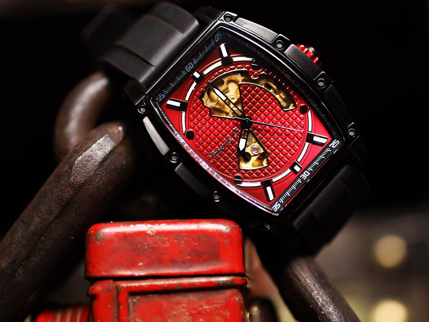 Luxury watch with red face and black strap on a dark background